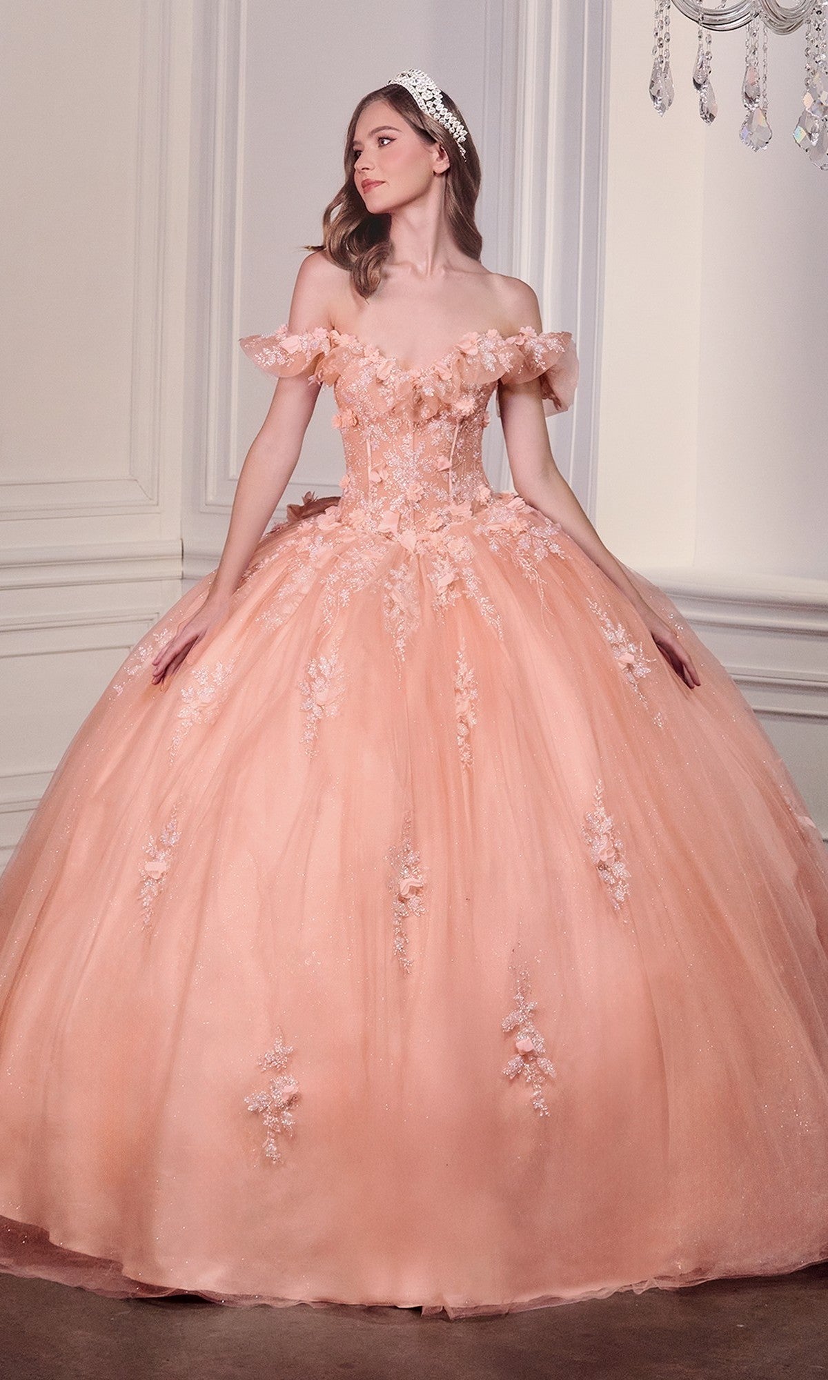 A woman wearing the Quinceanera Dress 15731 By Ladivine, featuring off-the-shoulder styling and 3D flowers, stands in an elegant white-paneled room.